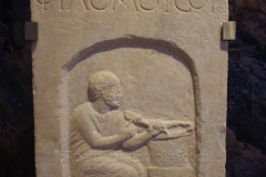 Funerary stele of Megistokoles, son of Philomousos. Megistokoles is depicted sculpting a krater, likely his profession in life. Dated to the 1st century BCE or 1st century CE. From Eretria. New Archaeological Museum of Chalkis.