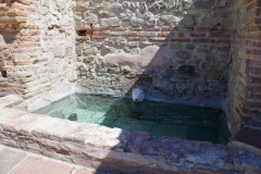 Smaller flanking pool on the north side of caldarium II in the bathing complex, with replica lion spout (original in the archaeological museum).