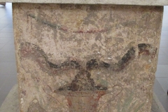 Detail of the altar from Domus 2b showing two snakes eating a pine cone out of a crater.